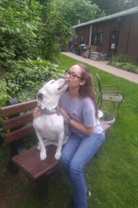 dog getting kisses while sitting on a bench with a staff member